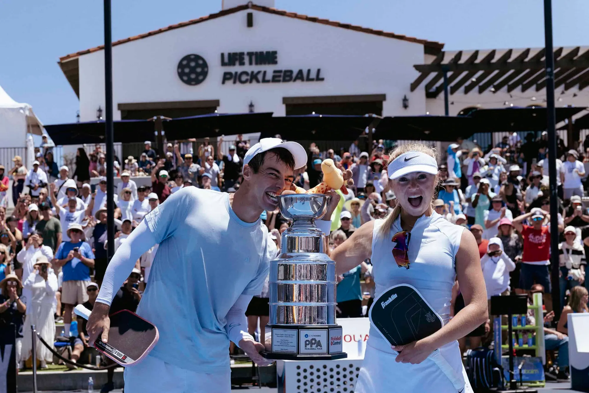 Celebrating victory at the PPA Tour pickleball tournament with players holding the trophy.